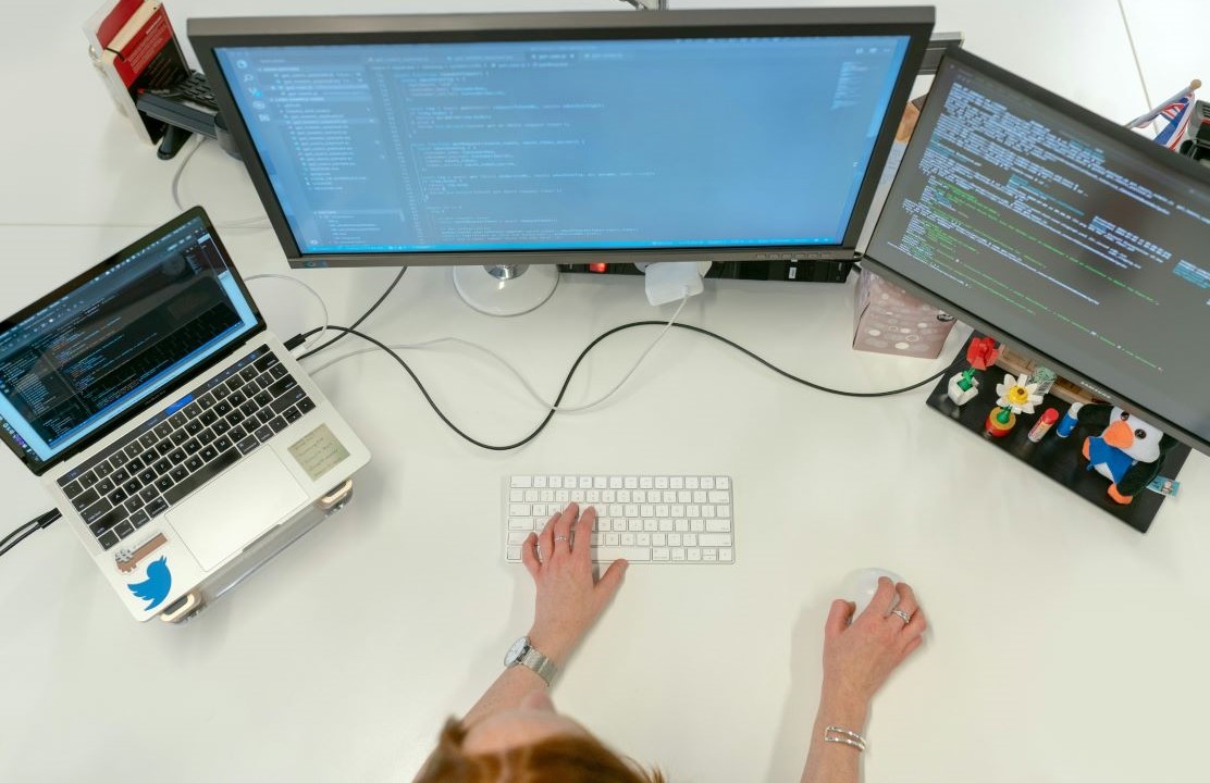 Female software engineer codes at her desk with computers.jpg