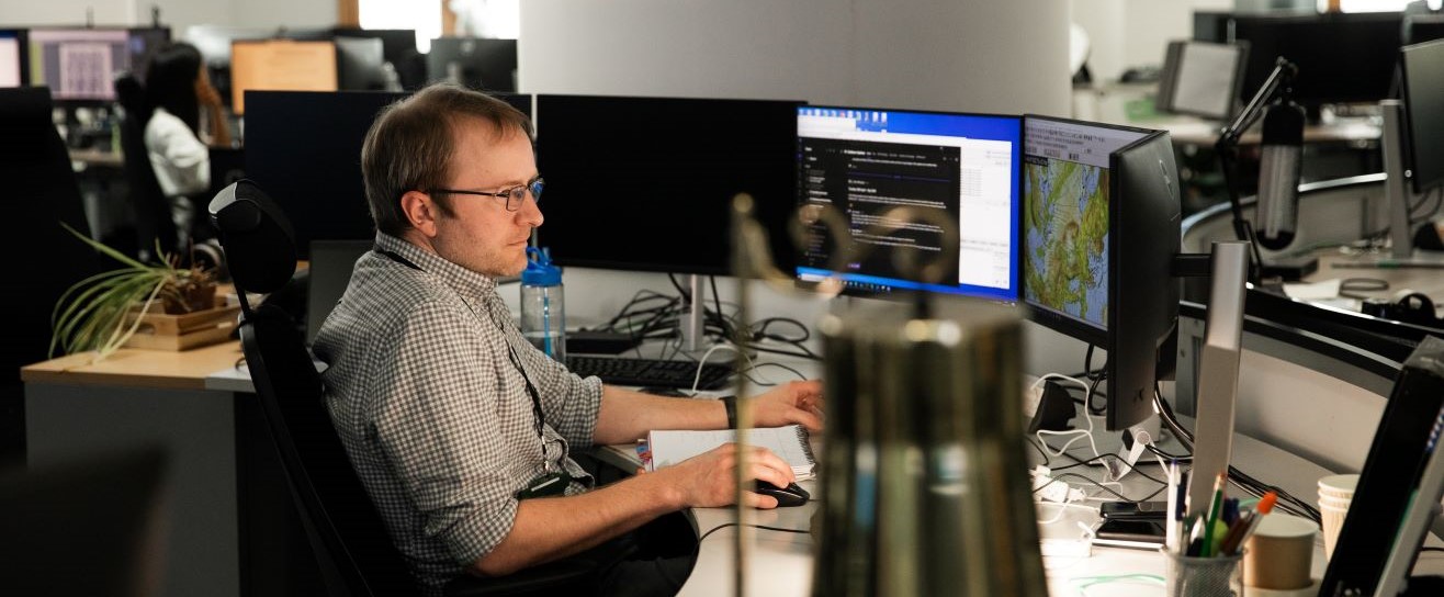 Man at a desk with multiple screens - letterbox.jpg